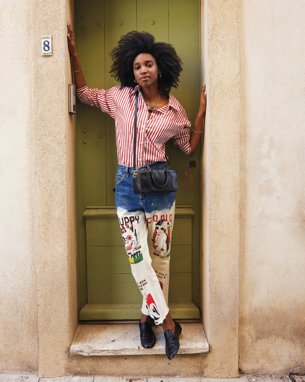 Model wearing the Red Emiliette Shirt and carrying the Black Petit Claudine.