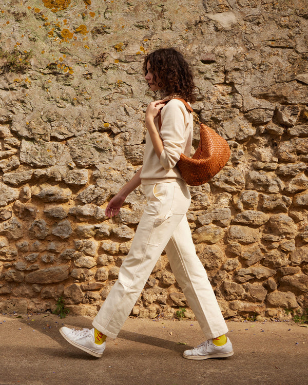 Celia carries the Natural Woven Checker Moyen Messenger on her shoulder