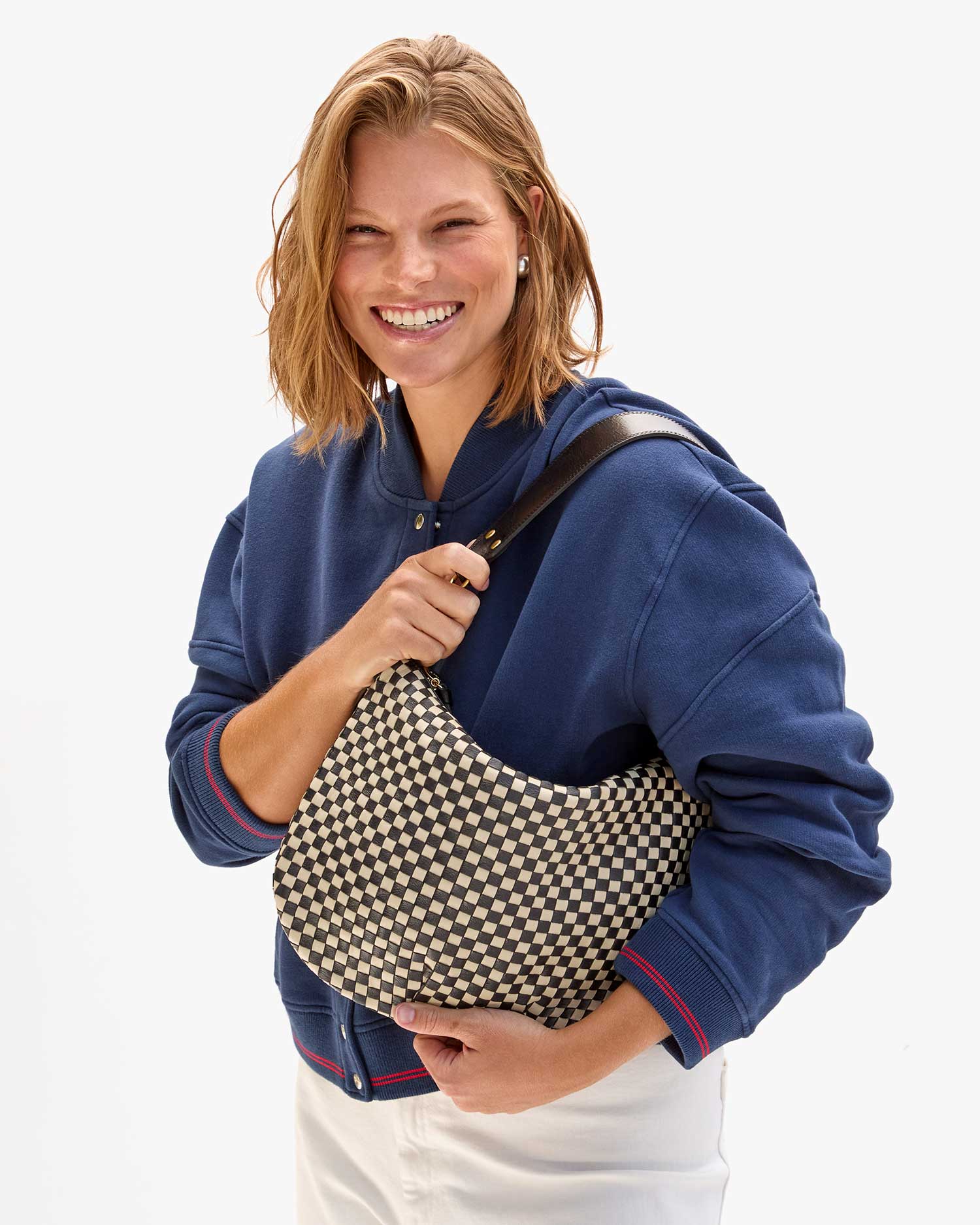 Sonnie holds the Moyen Messenger in Black and Cream Woven Checker with both hands