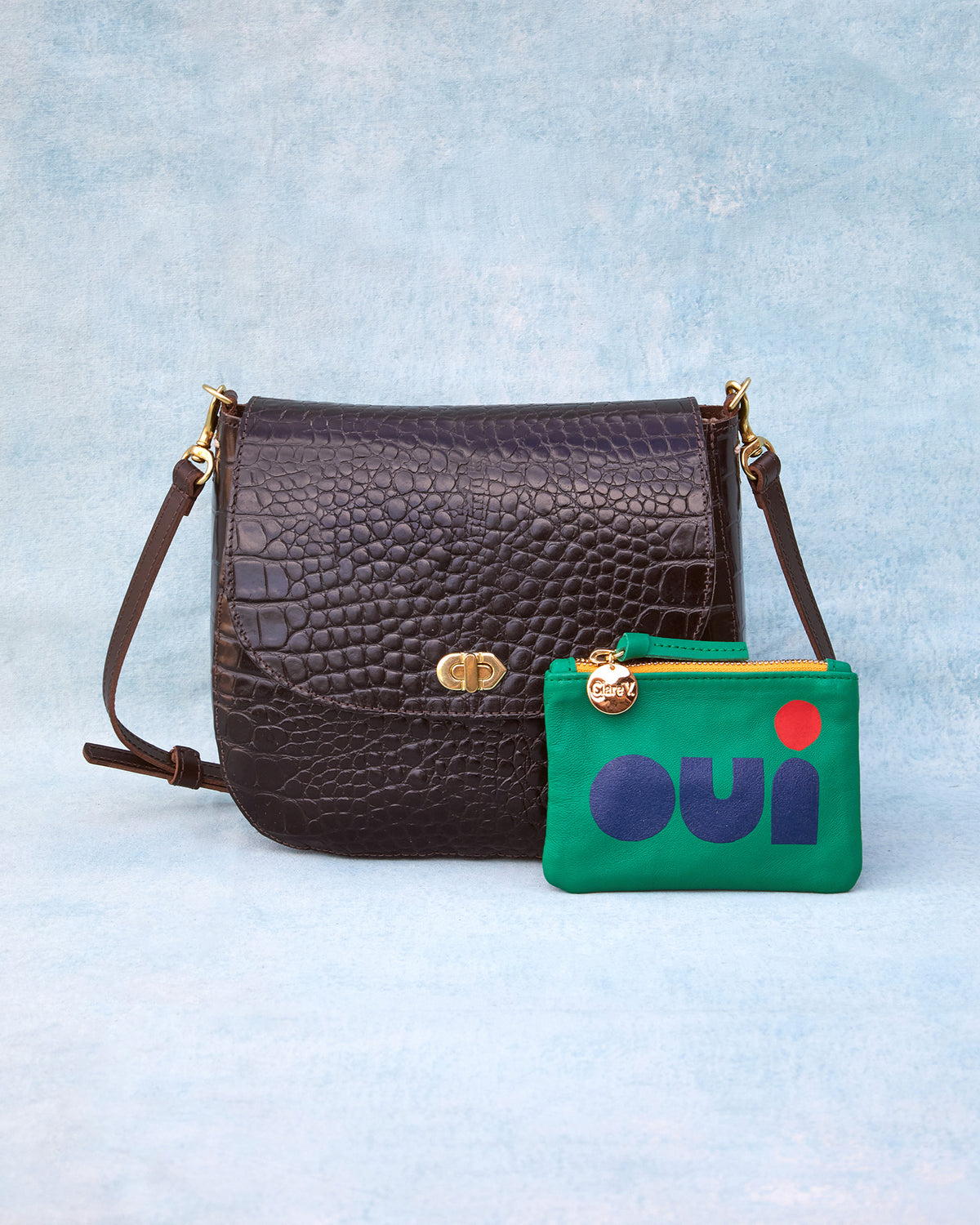 Turnlock Louis in Kalamata Croco next to a Oui Green Coin Clutch.