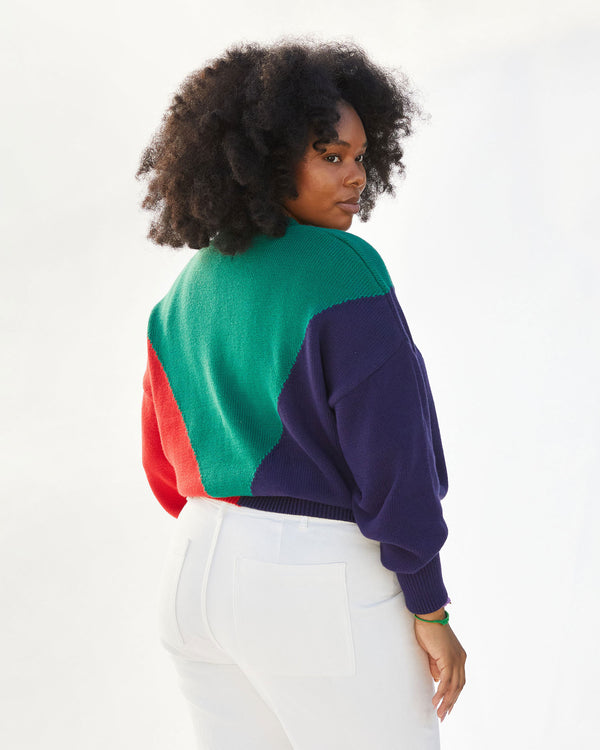 Back view of Candace in the Green, Navy and Poppy Drop Shoulder Sweater with white jeans