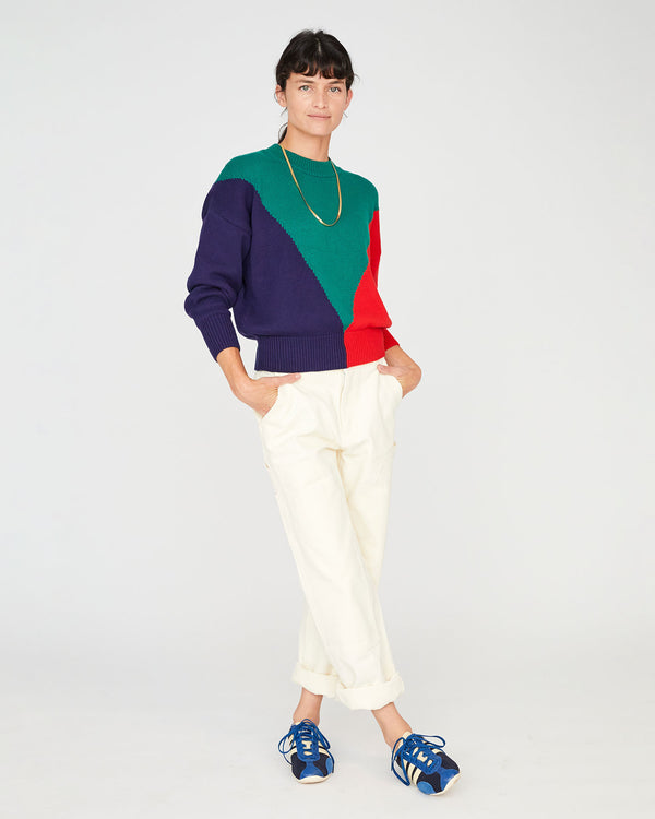 Danica with her hands in the pockets of her white pants , wearing the Green, Navy and Poppy Drop Shoulder Sweater and blue sneakers