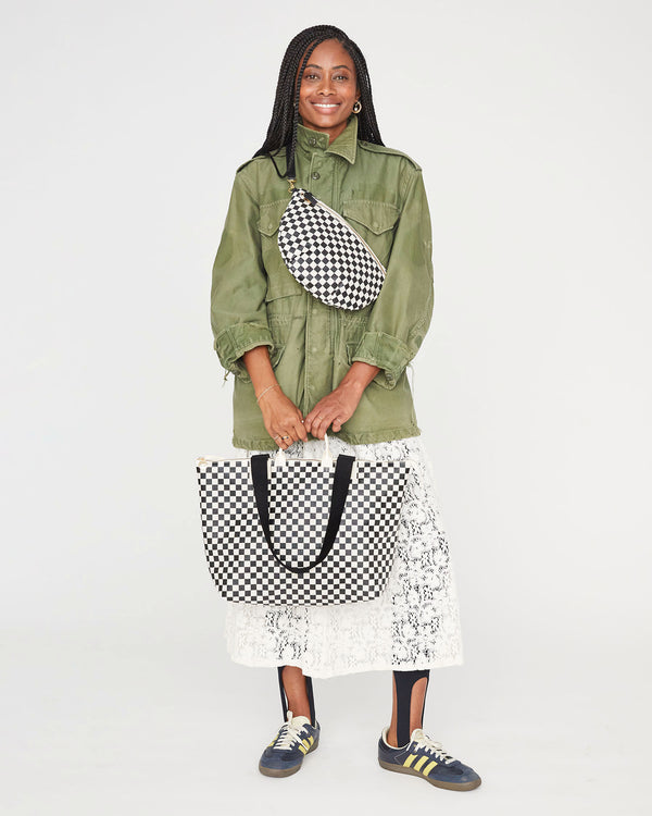 Mecca carrying the Black & Cream Checkers Le Zip Sac by its top handles. she's wearing a cream lace skirt and an army green coat with the black and cream checkers grande fanny worn around her chest