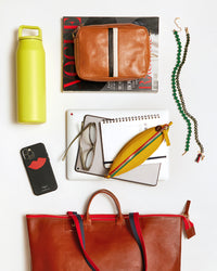 Miel Le Zip sac and the things that fit inside of it. These items include a yellow water bottl, an iphone, a vogue magazine, a midi sac, a laptop, an ipad, a small notebook, a pair of glasses, la banane in canary and two clare v necklaces